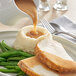A plate with turkey, mashed potatoes, and Campbell's turkey gravy being poured over it.