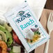 A Ken's Foods ranch dressing packet on a plate of salad.