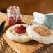 A wooden cutting board with two Thomas' Sandwich Size English Muffins with jam on them.
