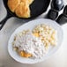 A plate of food with Chef-Mate country sausage gravy and potatoes next to a skillet.