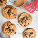 A close up of a David's Cookies Triple Chocolate Cookie with chocolate chips and chunks on top.