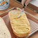 A person spreading Alpine Valley garlic butter on a piece of bread.