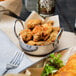A bowl of fried Boudreaux's breaded oysters with a fork on a white cloth.