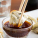 A bowl of General Tso's dipping sauce with chopsticks holding food.