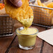 A person dipping food into a bowl of Gulden's Spicy Brown Mustard.