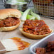 A close-up of a barbecue sandwich with Sweet Baby Ray's Sweet Red Chili Pepper Wing Sauce on top.