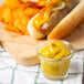 A hot dog and chips with French's Classic Yellow Mustard on a cutting board.