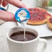 A person pouring International Delight French Vanilla non-dairy creamer into a cup of coffee.
