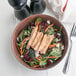 A bowl of salad with fajita chicken strips, carrots, and cranberries.