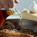 A person pouring AAK Jolina Marsala cooking wine into a pan of food.