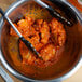 A bowl of Texas Pete Mild Buffalo Style Chicken Wing Sauce with tongs holding chicken wings.