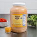 A case of Ken's Foods Golden Italian dressing on a counter next to bowls of lettuce and cherry tomatoes.
