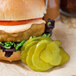 A burger with Harvest Fresh Dill Pickle slices on a white background.