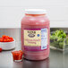 A large plastic container of Ken's Foods California French Dressing on a table next to a bowl of salad.