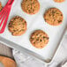 Preformed David's Cookies oatmeal raisin cookies on a baking sheet with a red spatula.