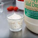 A small glass cup with white liquid next to a bottle of Ken's Foods salad dressing.