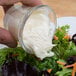 A person using a carrot to dip salad into a jar of Ken's Foods Whipped Salad Dressing.