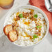 A bowl of Grassland small curd cottage cheese with croutons and a spoon.