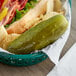 A plate with a sandwich and a B&G San-Del whole kosher dill pickle.