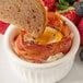 A piece of bread being dipped into a breakfast dish with Hatfield bacon.