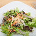 A plate of salad with Ken's Creamy Caesar Dressing on a table.