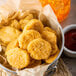 A bag of Tyson Breaded Chicken Nuggets in front of a bucket of ketchup.