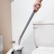 A hand holding the Unger Ergo toilet bowl swab cleaning a toilet.