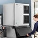 A woman standing next to a large Hoshizaki air cooled ice machine.
