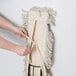 A person's hands using a Lavex all-in-one cotton mop with a black metal handle.