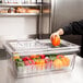 A person putting a yellow bell pepper into a Cambro food storage container.