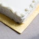 A white cake with frosting on a gold Enjay cake board.