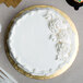 A white cake with gold frosting on a gold Enjay round cake drum.