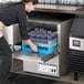 A woman putting glasses in a Jackson Undercounter Dishwasher on a counter in a professional kitchen.