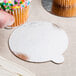 A finger holding a cupcake with sprinkles on a silver and gold Enjay dessert board.