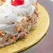 A close up of a cake on a gold round cake drum with a cherry on top.