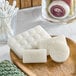 A wooden tray with Noble Eco Novo Natura wrapped white soap bars and cotton buds.