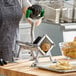 A heavy-duty French fry cutter with suction cup feet being used to cut potatoes into fries.
