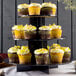 A Enjay 3-tier black cupcake stand holding cupcakes with yellow frosting.