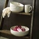 A ladder with Oneida marble porcelain bowls and a mug on it.