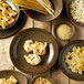 A Oneida Rustic chestnut porcelain deep coupe plate with pasta on a wood table.
