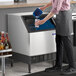 A man pouring water into a Manitowoc undercounter ice machine.