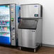 A Manitowoc air cooled ice machine next to a soda machine in a corporate office cafeteria.