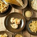 A table set with Oneida Rustic Chestnut porcelain coupe plates of pasta.