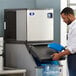 A man standing next to a Manitowoc blue air cooled ice machine.