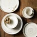 A stack of Oneida Marble porcelain plates on a table.