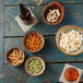 Oneida Rustic by 1880 Hospitality Sama Porcelain Bowls filled with popcorn, peanuts, and peas on a table.