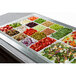 A white sandstone Bon Chef square bowl filled with tomatoes on a salad bar counter.