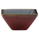 A close-up of a square crimson porcelain ramekin with a black center.