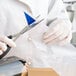 A person cutting a plastic bag with scissors.