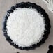 An Enjay black laminated corrugated cake circle with a white cake on top.